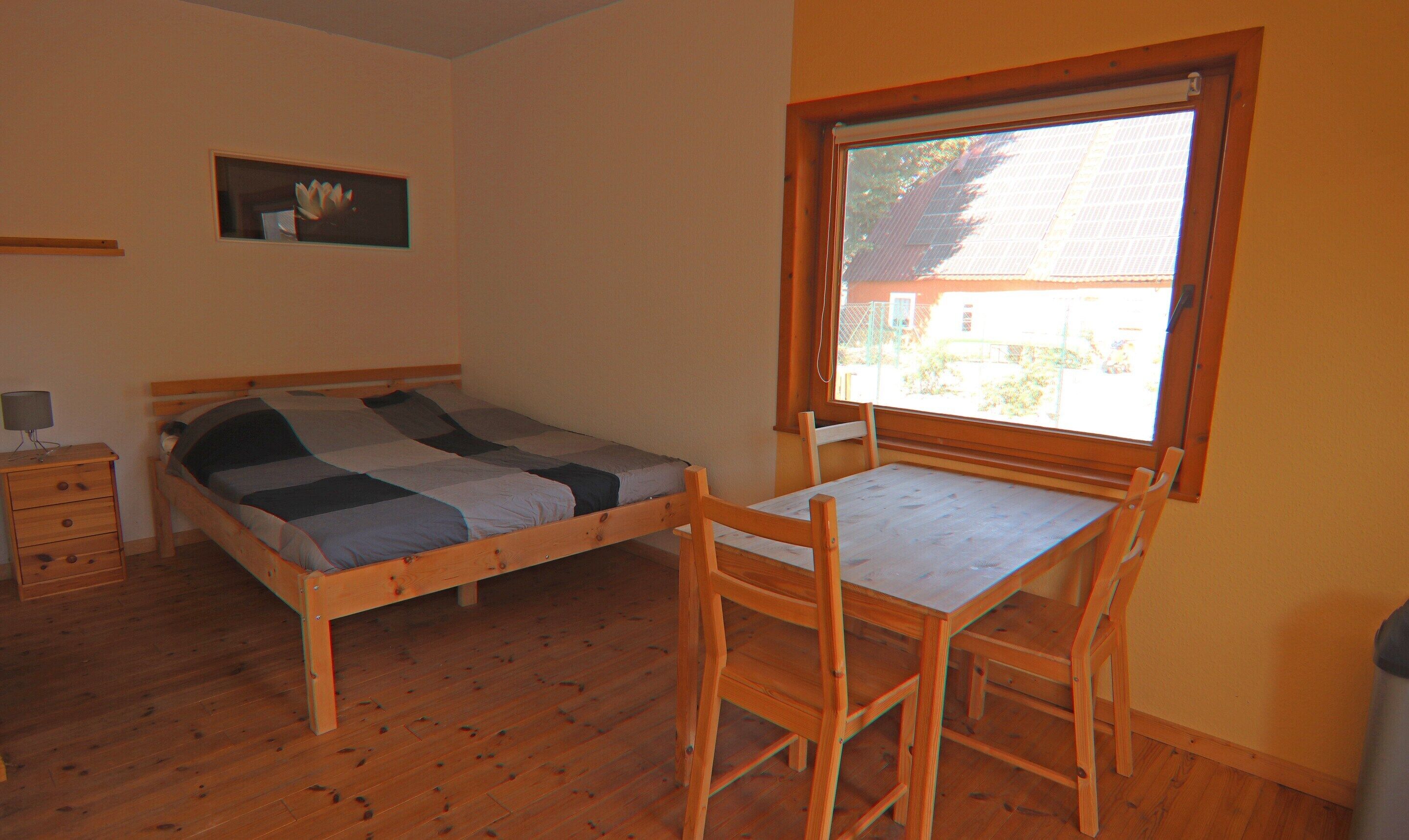 A bedroom with a wooden bed, a desk, and a chair.