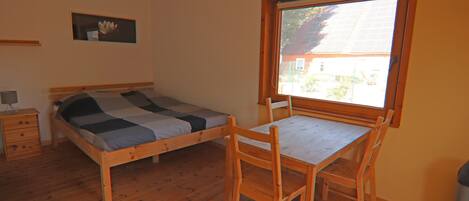 A bedroom with a wooden bed, a desk, and a chair.
