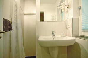 A bathroom with a white sink, a mirror, and a hairdryer on the wall. - Doppelhaushalfte Luv in Zingst (Zingst)