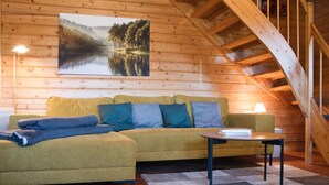 En ombonad träinredning med en soffa, ett bord och en målning av en sjö.