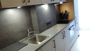 Eine moderne Küche mit Edelstahlgeräten, einem Spülbecken und einer schwarzen Matte auf der Arbeitsplatte.