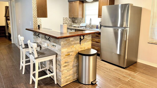 A modern kitchen with a stone island, stainless steel appliances, and wooden cabinets. - Peaceful and Beautiful Home (Brandon)