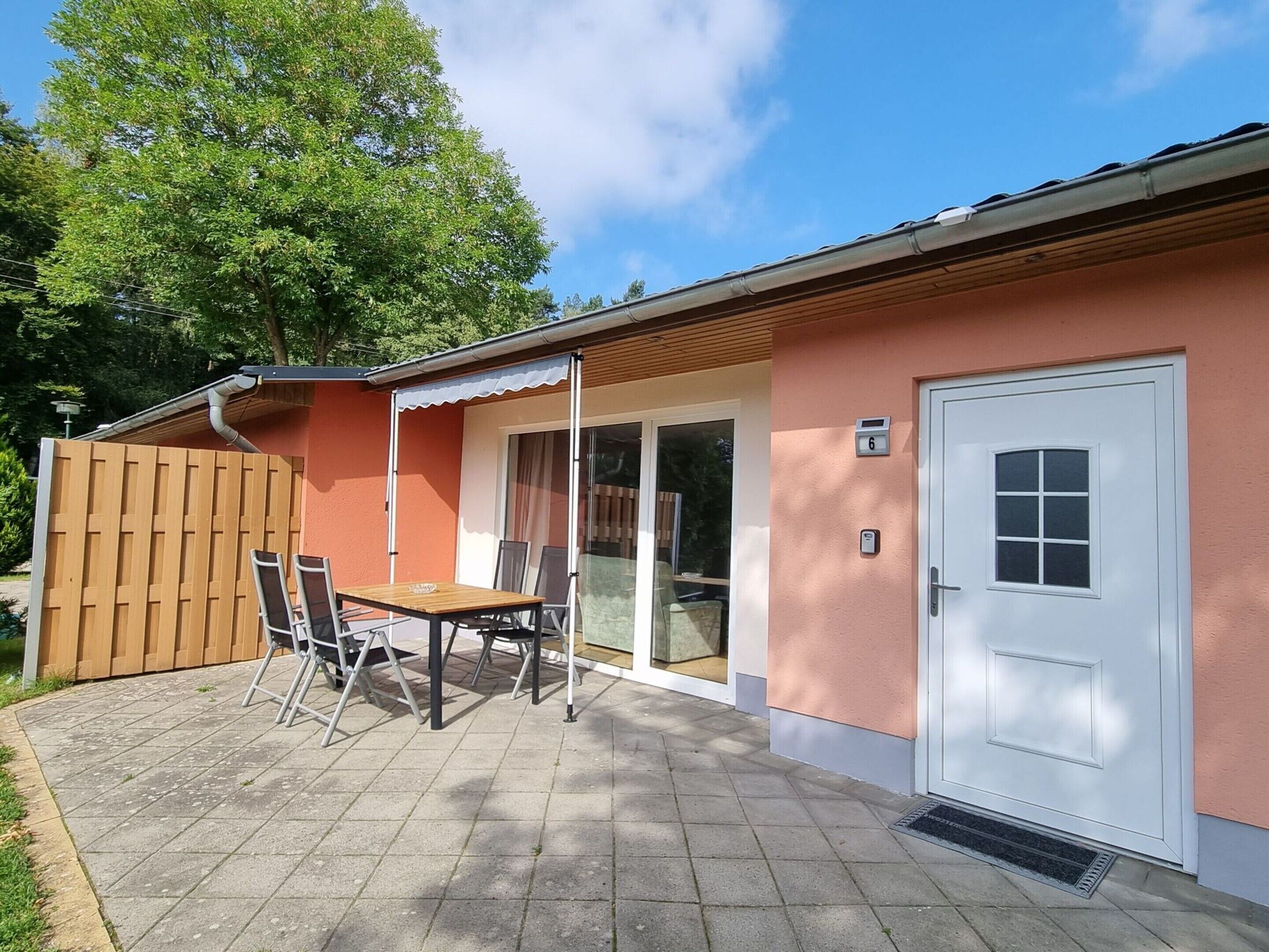 Ein Patio mit Tisch und Stühlen, einem Holzzaun und einer Tür mit einer Nummer.