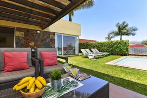 A modern outdoor seating area with a pool, a stone wall, and a view of the landscape.