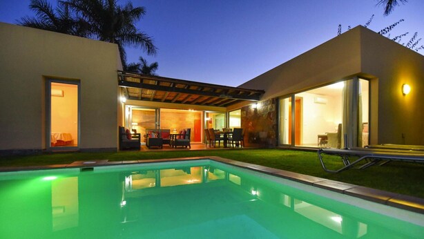 Uma casa moderna com piscina, varanda coberta e interior bem iluminado.