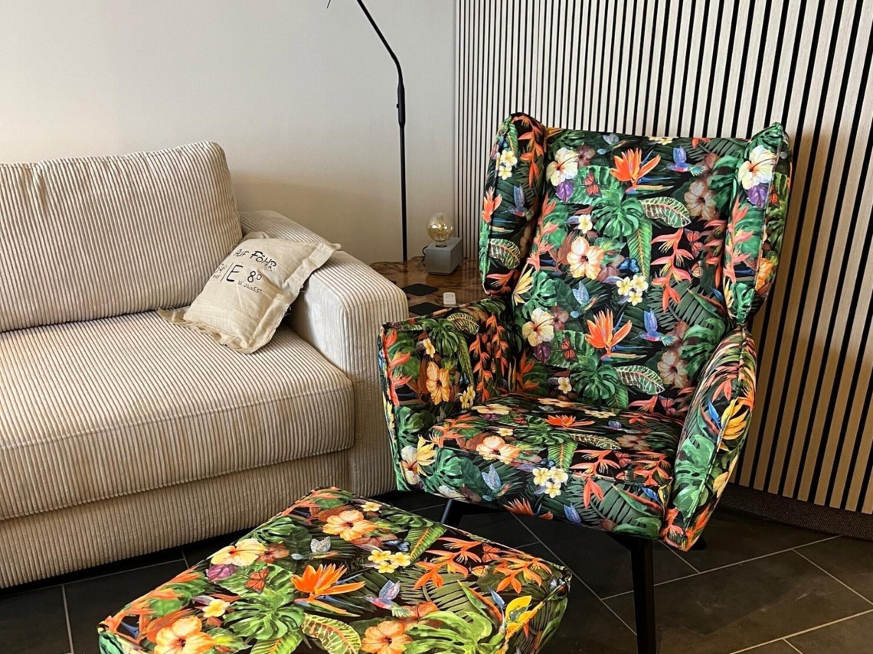 A striped sofa with a pillow and a floral armchair with a matching ottoman.