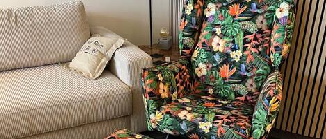 A striped sofa with a pillow and a floral armchair with a matching ottoman.