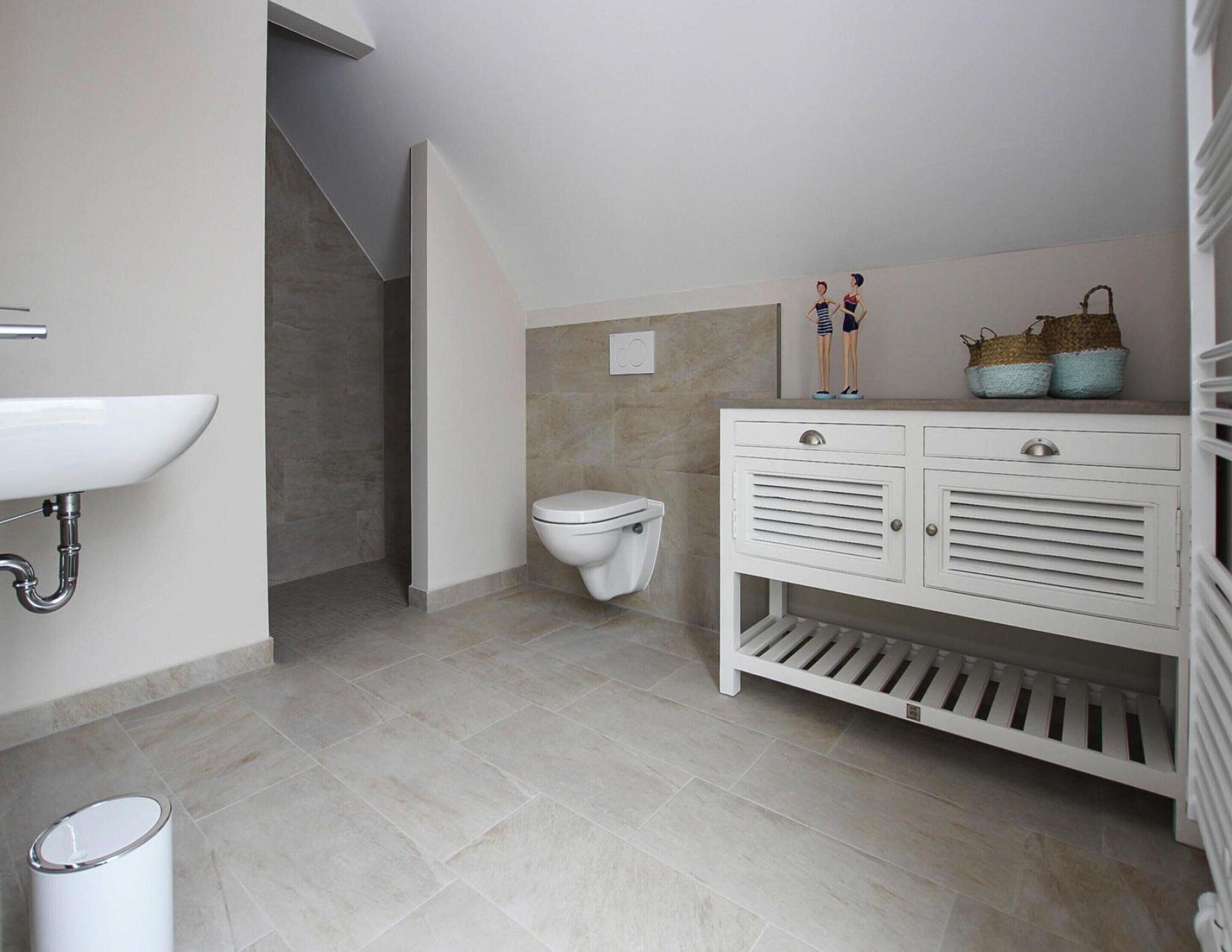 Un baño con lavamanos, inodoro y tocador blanco con cajones de almacenamiento.