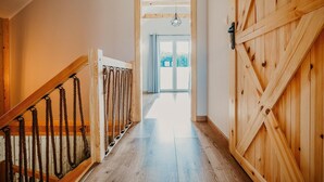 Un escalier en bois, doté de rampes en corde, mène à une porte ornée d’un motif géométrique.