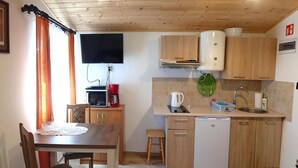 Ett kompakt kök med träskåp, en mikrovågsugn, en kaffebryggare, en vattenkokare, en diskmaskin och ett handfat.