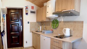 Ett kompakt kök med träskåp, en inbyggd diskmaskin, en diskho och en vattenkokare.