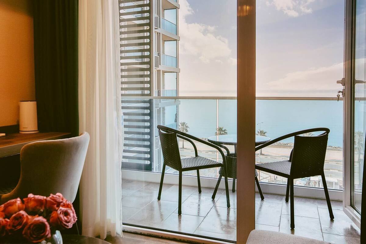Ein Hotelzimmer mit Balkon, einem Esstisch mit Stühlen und einem Blumenstrauß.