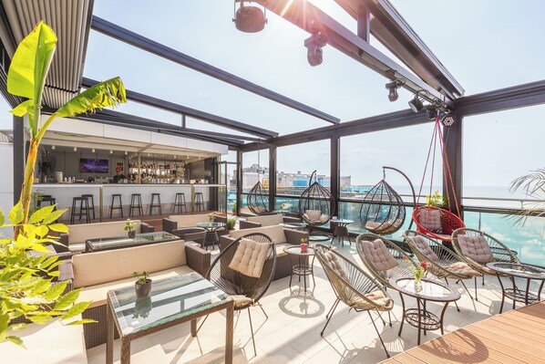 Eine Dachterrasse mit Außenbereich, Bar und Meerblick.