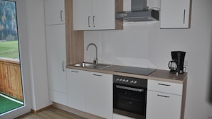 Una cocina moderna con armarios blancos, un lavamanos de acero inoxidable, un horno empotrado y una cafetera.