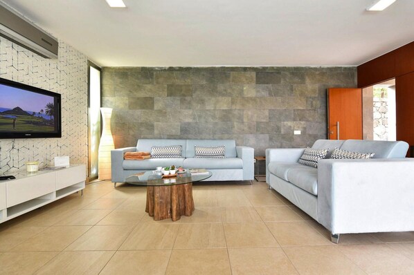 A modern living room with a grey sofa set, a wooden coffee table, and a flat-screen TV mounted on the wall. - Holiday Home, Maspalomas (San Bartolomé de Tirajana)