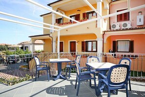 Guests can enjoy the patio area with comfortable seating and tables, surrounded by the building's unique facade and multiple balconies.
