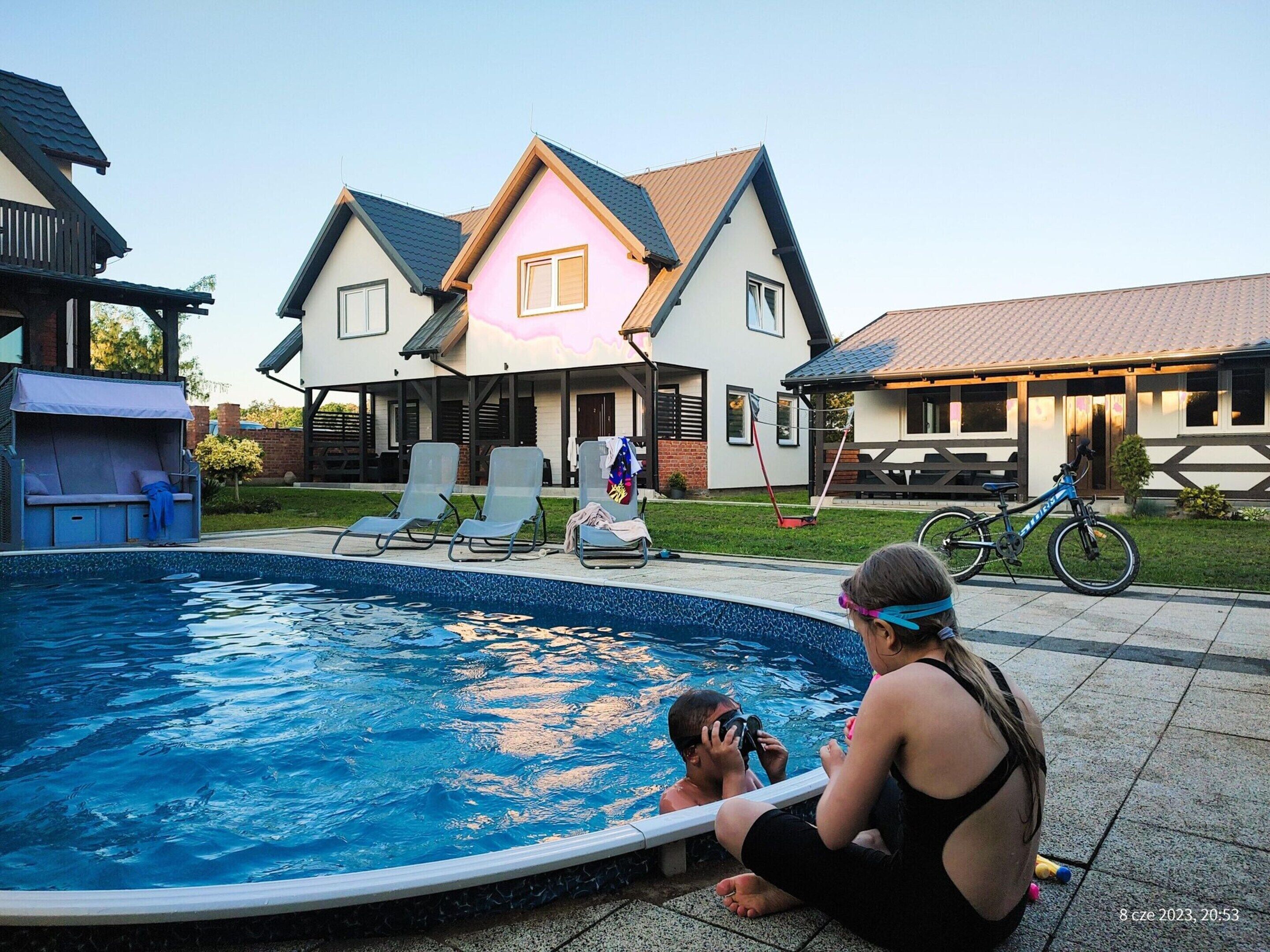 A swimming pool with lounge chairs and a house in the background.