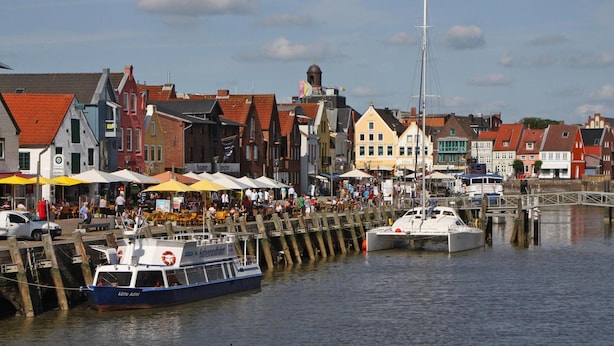 A waterfront area with colorful buildings, a dock with boats, and a pedestrian bridge. - Ferienhaus fur bis zu 6 Personen, Am Wung in Husum (Husum)
