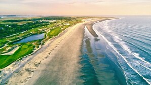 Oversigtsbillede af et kystområde med strand, golfbane og hav.