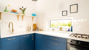 A modern kitchen with blue cabinets, white countertops, and a window providing natural light. - Cottage in the Middle of Nature, Pilwa (Wegorzewo)