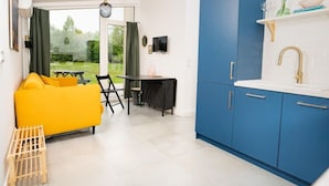 A modern kitchen with blue cabinets, a yellow sofa, and a dining area with a table and chairs. - Cottage in the Middle of Nature, Pilwa (Wegorzewo)