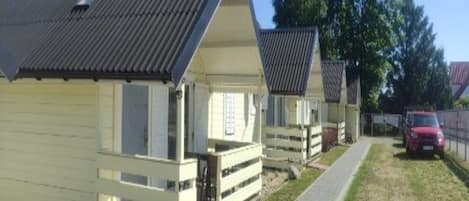 A row of white cabins with sloped roofs, each with a small porch and a window.