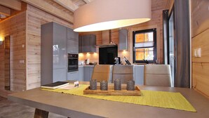 A modern kitchen with wooden cabinetry, a central island, and a dining area with a large table and chairs. - Ferienhaus, Schierke (Wernigerode)
