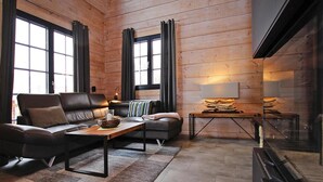 A modern living room with a leather sofa, a wooden coffee table, and a fireplace. - Ferienhaus, Schierke (Wernigerode)