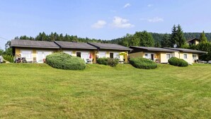 A row of yellow buildings with satellite dishes, surrounded by well-maintained lawns and trees. - Bungalow on Lake Klopein With a Terrace (Sankt Kanzian am Klopeiner See)
