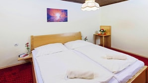 A double bed with white linens and towels, a bedside table with a book and a vase of flowers, a wall-mounted painting, and a hanging light fixture. - Bungalow on Lake Klopein With a Terrace (Sankt Kanzian am Klopeiner See)