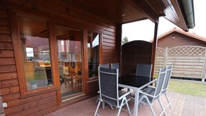 A wooden cabin with a patio area featuring a table and chairs. - Doppelhaushalfte in Hasselfelde (Oberharz am Brocken)