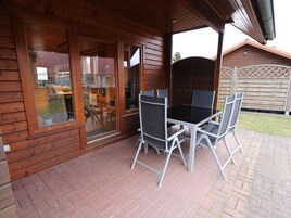 Una cabaña de madera con un patio que tiene una mesa y sillas.