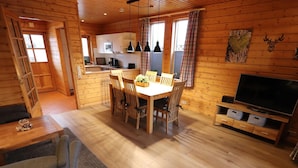 A cozy cabin interior with a dining area, kitchen, and a TV. - Doppelhaushalfte in Hasselfelde (Oberharz am Brocken)