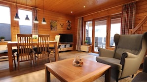 A cozy wooden cabin interior with a dining area, a sofa, and a television. - Doppelhaushalfte in Hasselfelde (Oberharz am Brocken)