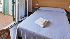 A hotel room with a bed, a nightstand, a green door, and a sliding glass door leading to an outdoor area. - Apartment in Pietra Ligure (Pietra Ligure)