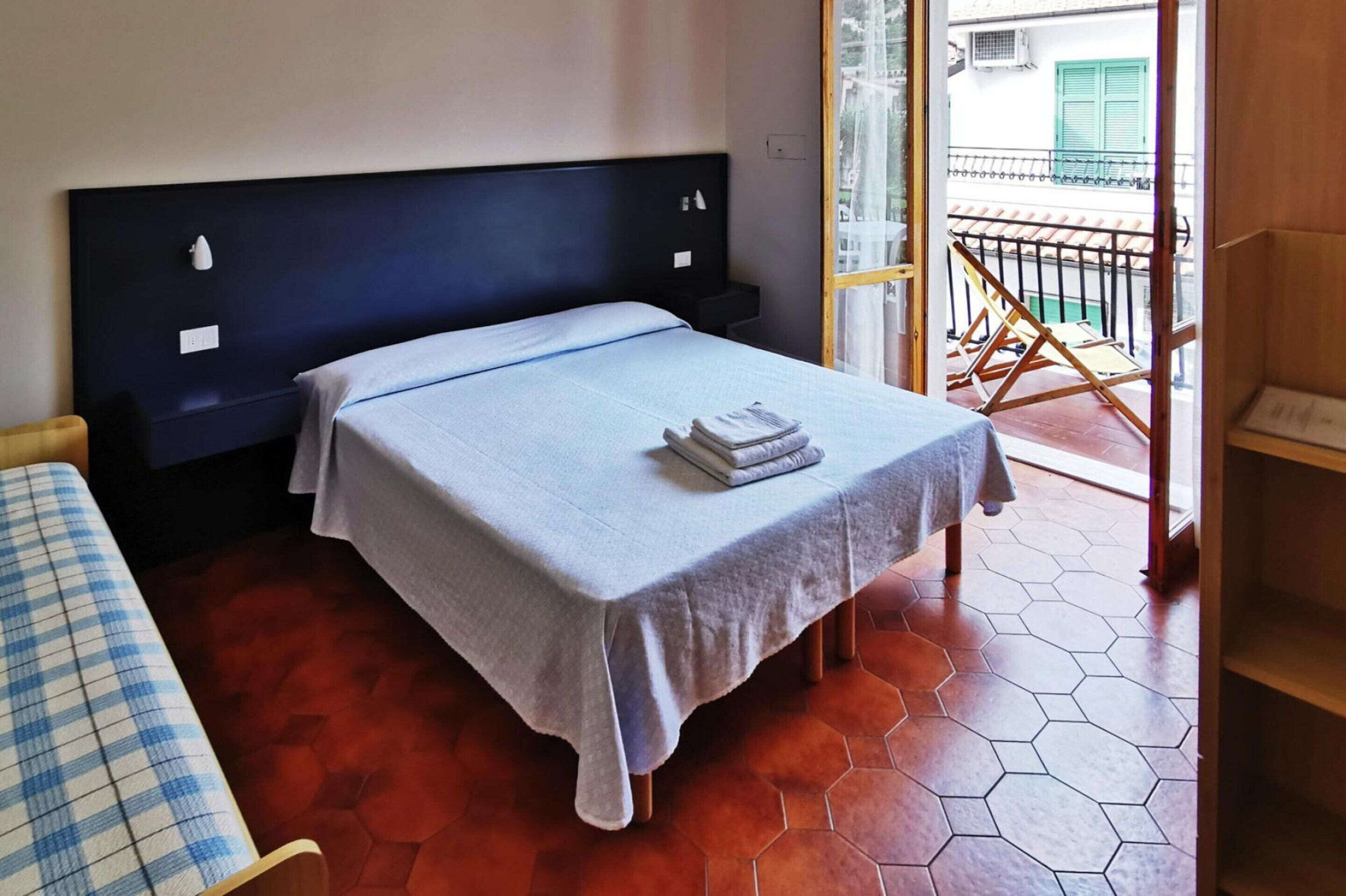 Une chambre avec un lit, un banc et une vue sur un balcon.