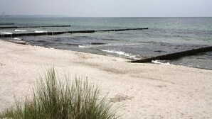A beach with sand and waves, a wooden pier, and a cloudy sky. - Ferienpark Markgrafenheide (Rostock)