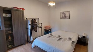 Et soveværelse med seng, garderobeskab, knagerække, natbord og et billede på væggen.