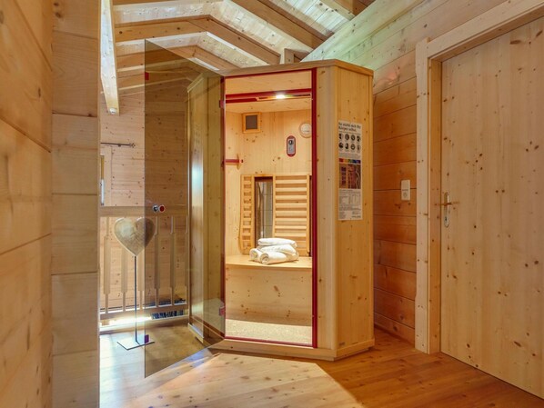 A wooden sauna room with a glass door, a towel rack, and a sauna control panel. - Chalet in Fugen Near Spieljochbahn (Fuegen)