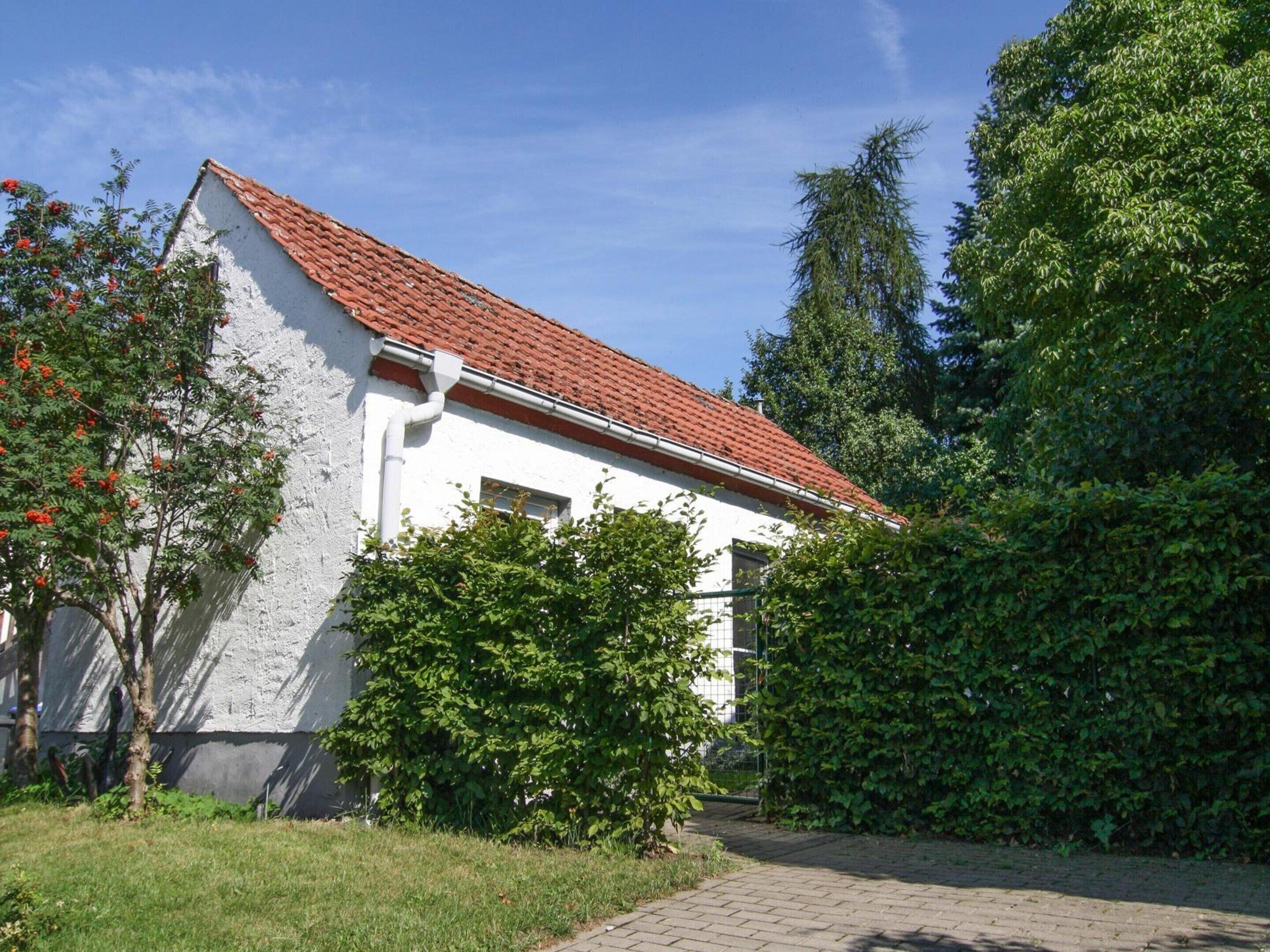 A white building with a red-tiled roof, surrounded by greenery and trees.