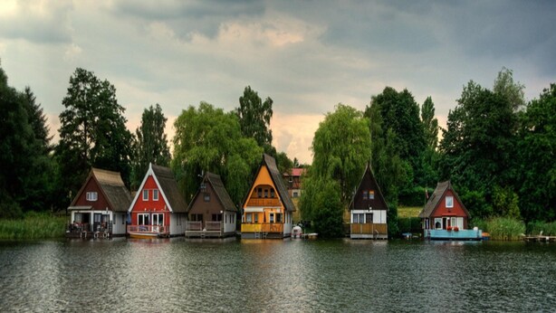 Un conjunto de casas tradicionales junto a un lago bajo un cielo nublado.