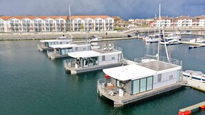 A marina with several docked boats and a building with a modern design. - Hausboot in Boltenhagen (Boltenhagen)