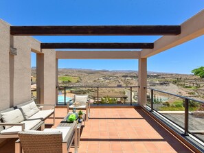 Un balcone con piscina, arredi da esterno e vista su un paesaggio collinare.