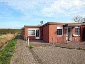 Un bâtiment en briques, doté d’une antenne parabolique, d’une petite porte et d’une fenêtre.