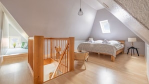 Ein Schlafzimmer mit einer Holztreppe, einem Bett, einem kleinen Tisch und einem Fenster.