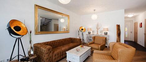 A living room with a large mirror, a brown sofa, a white coffee table, and a floor lamp.
