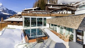 A modern ski resort with a glass-enclosed pool, wooden deck, and mountain views. - Apartment in Matrei in Osttirol With a Garage (Matrei in Osttirol)