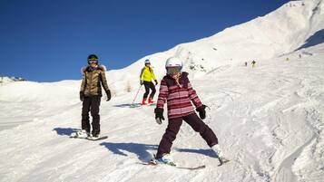 Pista de esquí nevada con esquiadores y snowboarders.