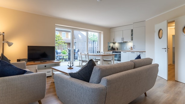 Un salon moderne avec un canapé, un téléviseur et un coin repas.