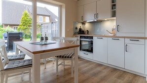 Une cuisine moderne avec des armoires blanches, un plan de travail en bois et une grande fenêtre donnant sur un jardin.